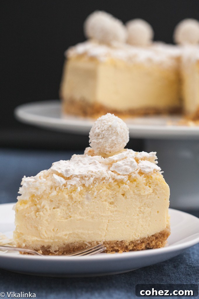 A perfectly sliced piece of Raffaello Cheesecake on a plate, with the remaining cake visible in the background, highlighting the distinct layers.