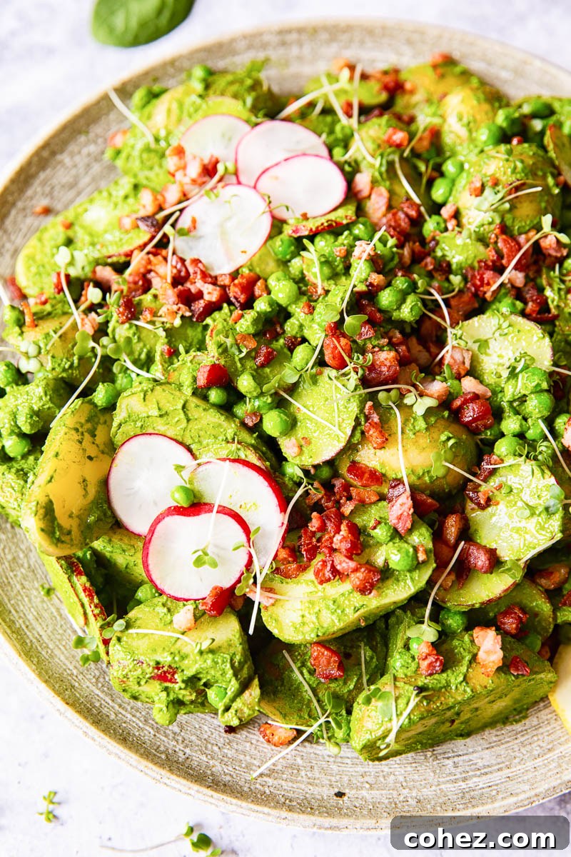 Fresh and vibrant pesto potato salad with radishes, peas and crispy bacon bits, served in a large bowl, perfect for picnics and BBQs.