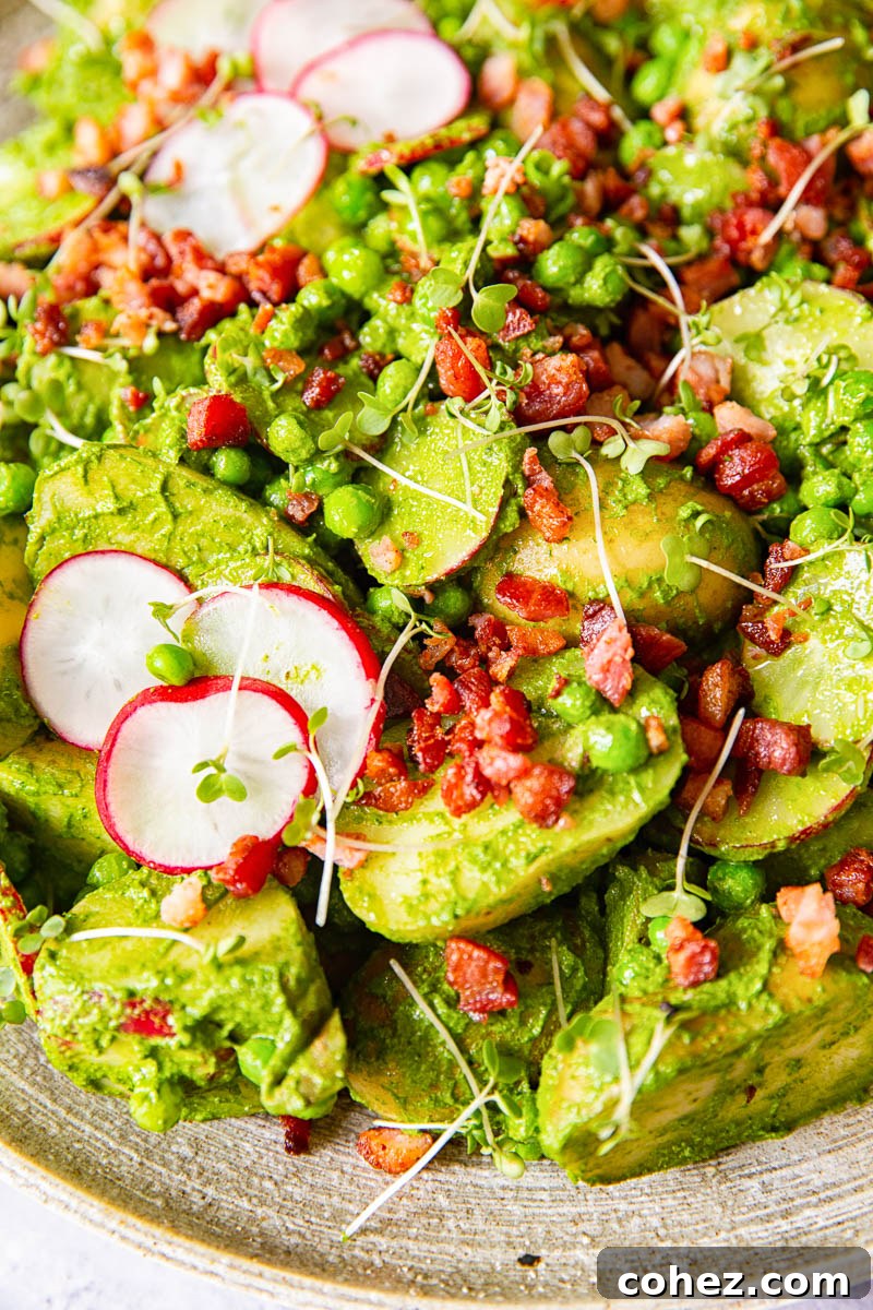 Pesto potato salad beautifully presented with thinly sliced radishes and generous bacon bits on top, ready for serving.