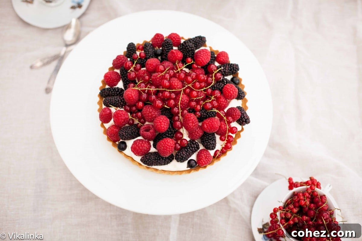 Sweet Summer Berry Bliss 4 Top down shot of a beautifully arranged berry tart on a white platter, highlighting its golden crust and colorful topping.