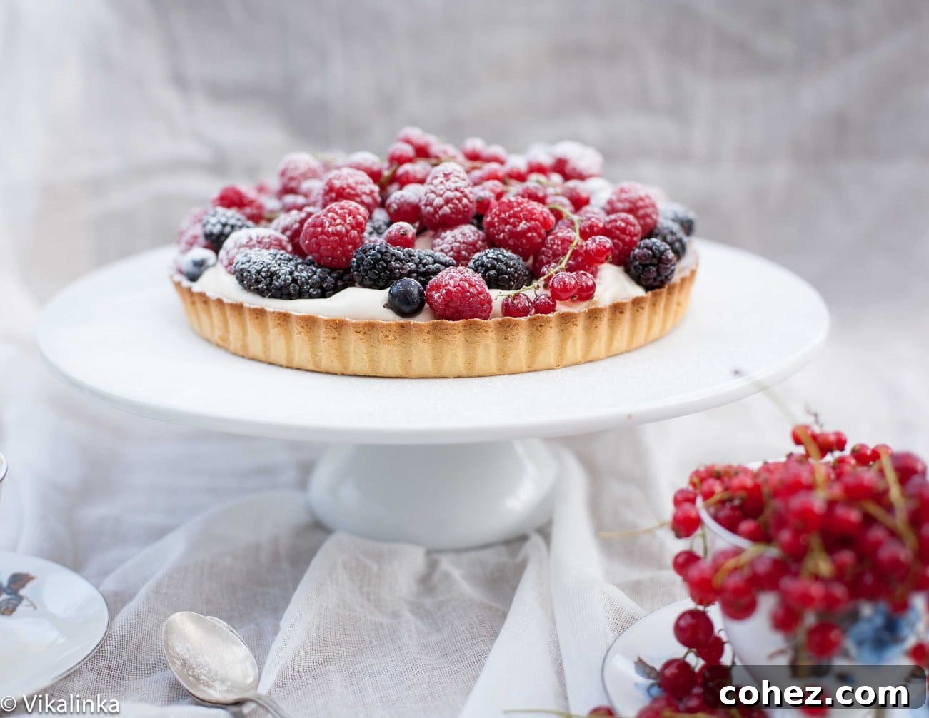 Sweet Summer Berry Bliss 7 A beautiful berry tart displayed on a serving stand, with fresh cranberries in the foreground, perfect for a gathering.