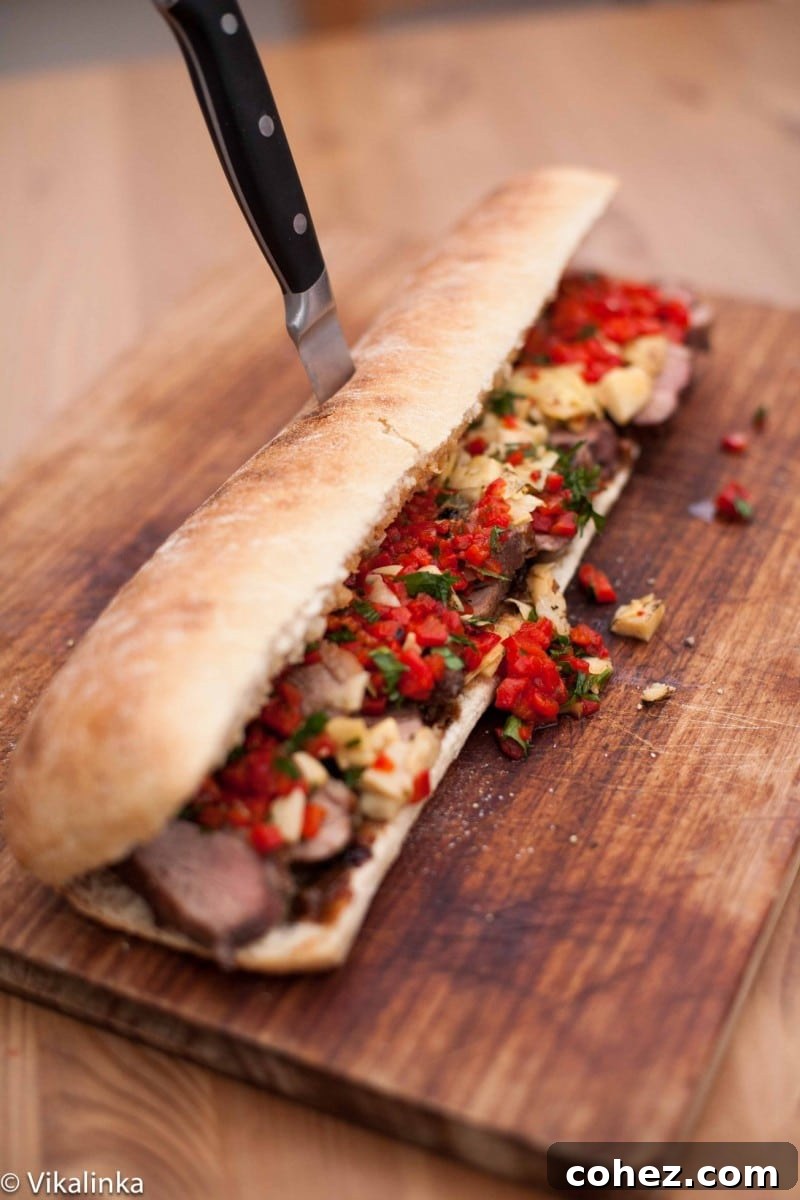 Side shot of a generously filled duck breast sandwich resting on a rustic wooden cutting board, ready to be sliced.