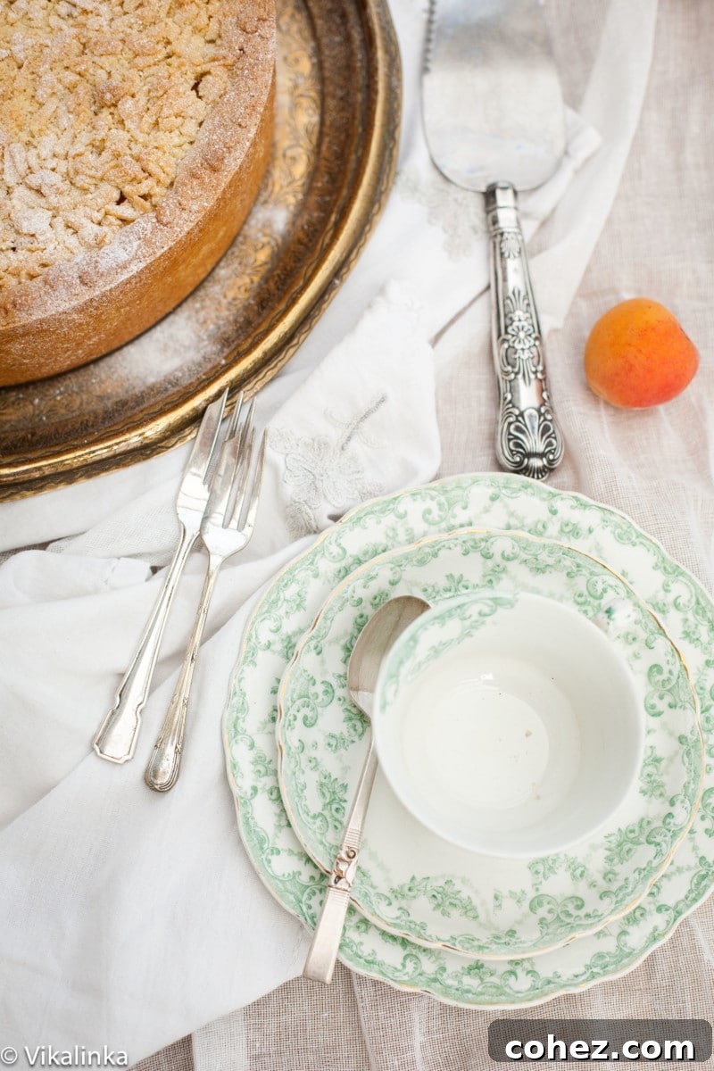 Apricot Crumble Cheesecake 3 A vintage teacup resting on a white tablecloth, with a piece of crumb apricot cheesecake subtly in the background, evoking a sense of cozy nostalgia.