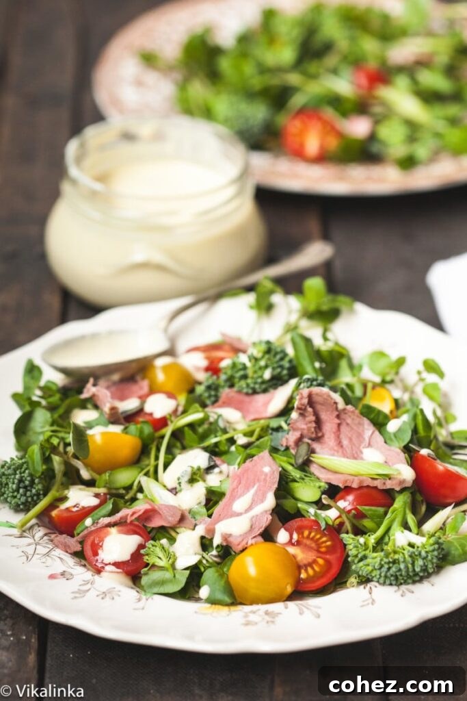 Bold Roast Beef and Watercress Salad with Zesty Horseradish Cream 2 Fresh watercress and roast beef salad, dressed and ready to eat, with a jar of horseradish dressing in the background.