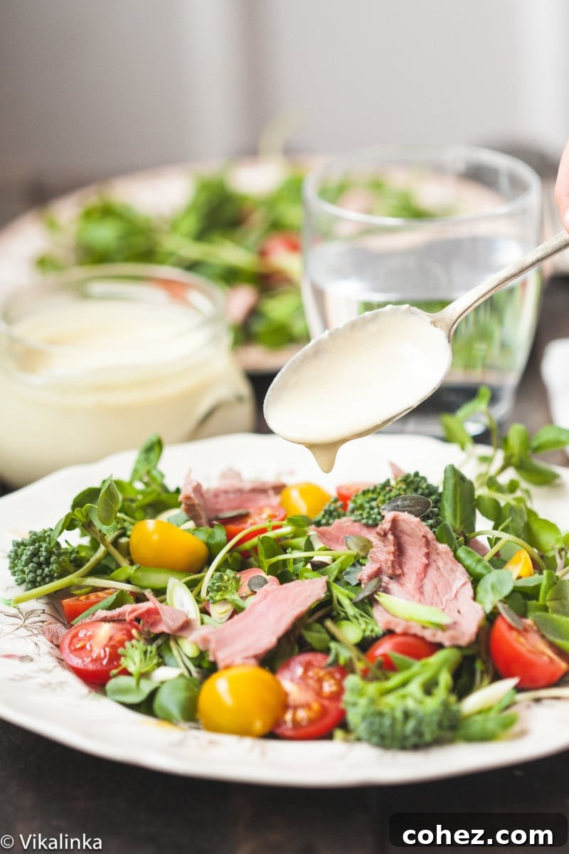 Bold Roast Beef and Watercress Salad with Zesty Horseradish Cream 3 Close-up of a vibrant watercress salad with thinly sliced roast beef on a white plate, highlighting its fresh ingredients.