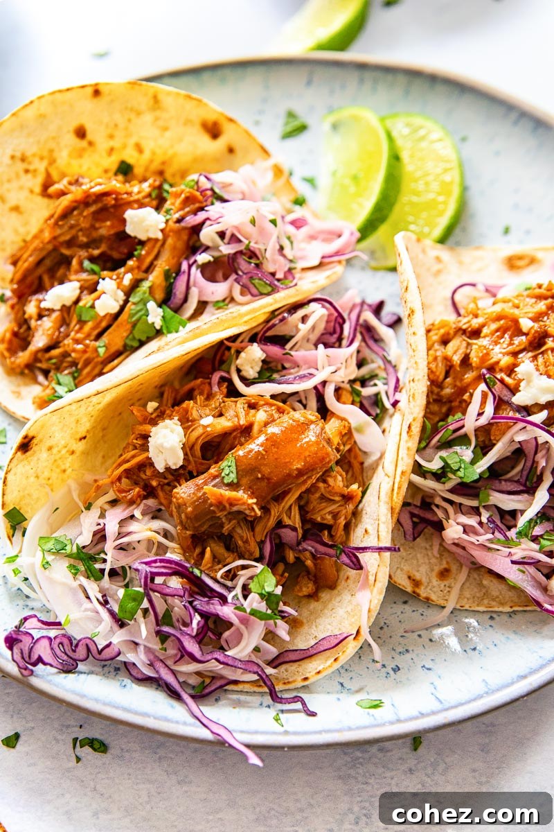 Three pulled pork tacos with creamy cilantro lime slaw on a blue plate