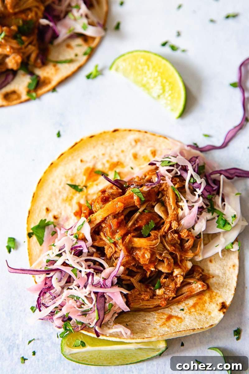 Close-up of a single soft taco topped with pulled pork and slaw, ready to eat
