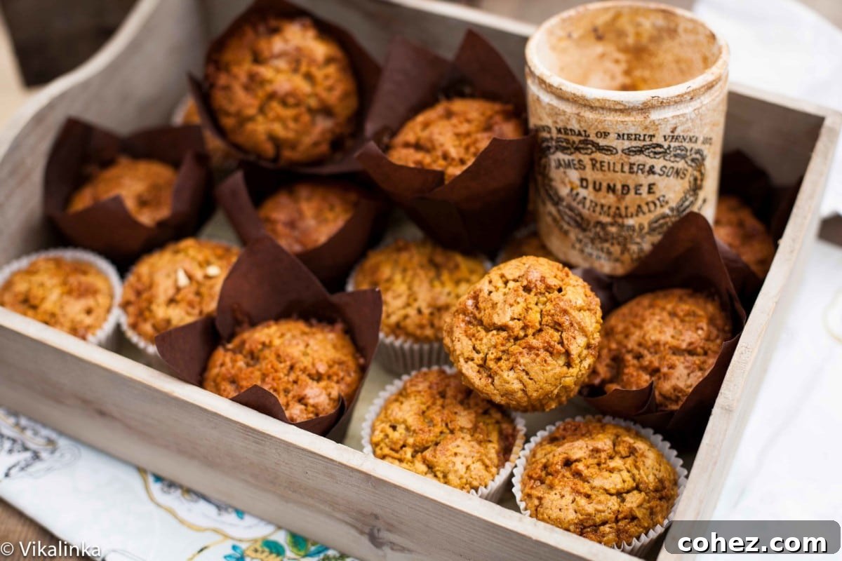 A collection of golden-brown Toffee Honeycomb Pumpkin Muffins nestled in a rustic wooden crate, with a glass jar filled with rich toffee pieces visible in the background