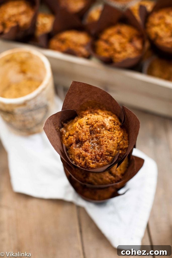 A perfectly stacked trio of golden-brown pumpkin muffins with toffee and honeycomb, emphasizing their fluffy texture and enticing golden tops, with more muffins blurred in the background