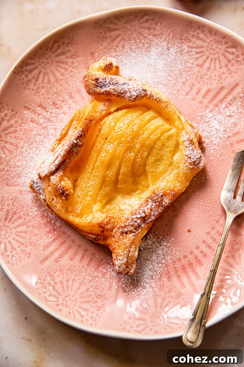 Close-up view of a baked pear tart, showing the flaky pastry and soft pear