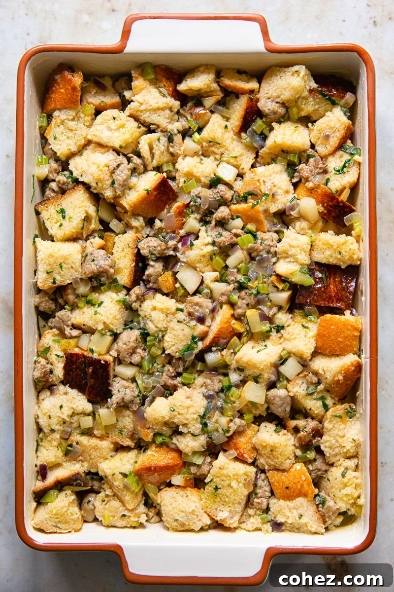 An unbaked sausage, pear, and sage stuffing mixture, neatly pressed into a rectangular baking pan, glistening and ready for the oven.