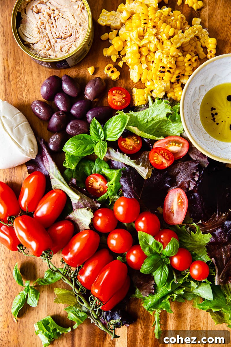 Fresh ingredients for Italian Salad arranged on a wooden cutting board, including cherry tomatoes, olives, corn, and mozzarella