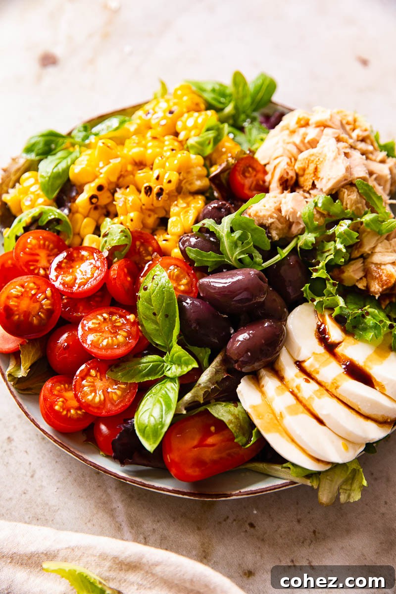 Plated Italian Salad with cherry tomatoes, tuna, corn, olives, and fresh mozzarella ready to serve on a rustic table