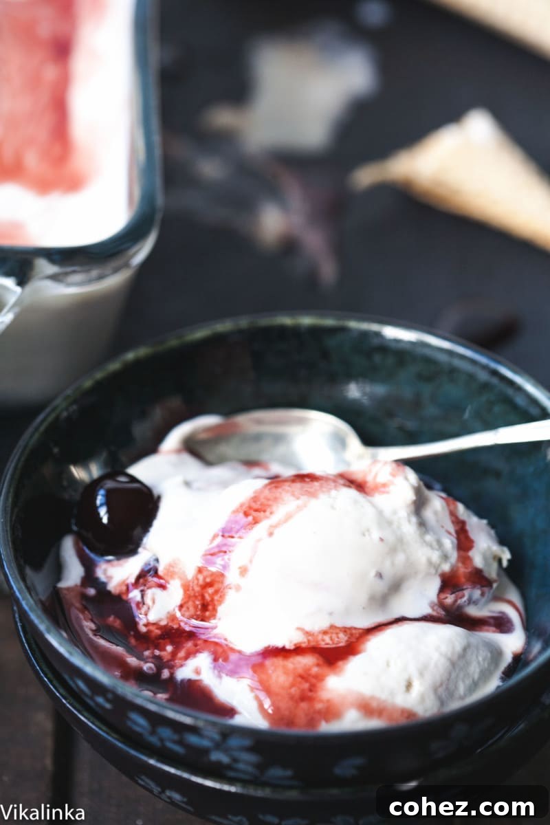 Close-up view of a bowl of creamy Amarena gelato with a spoon, highlighting its smooth texture and rich color.