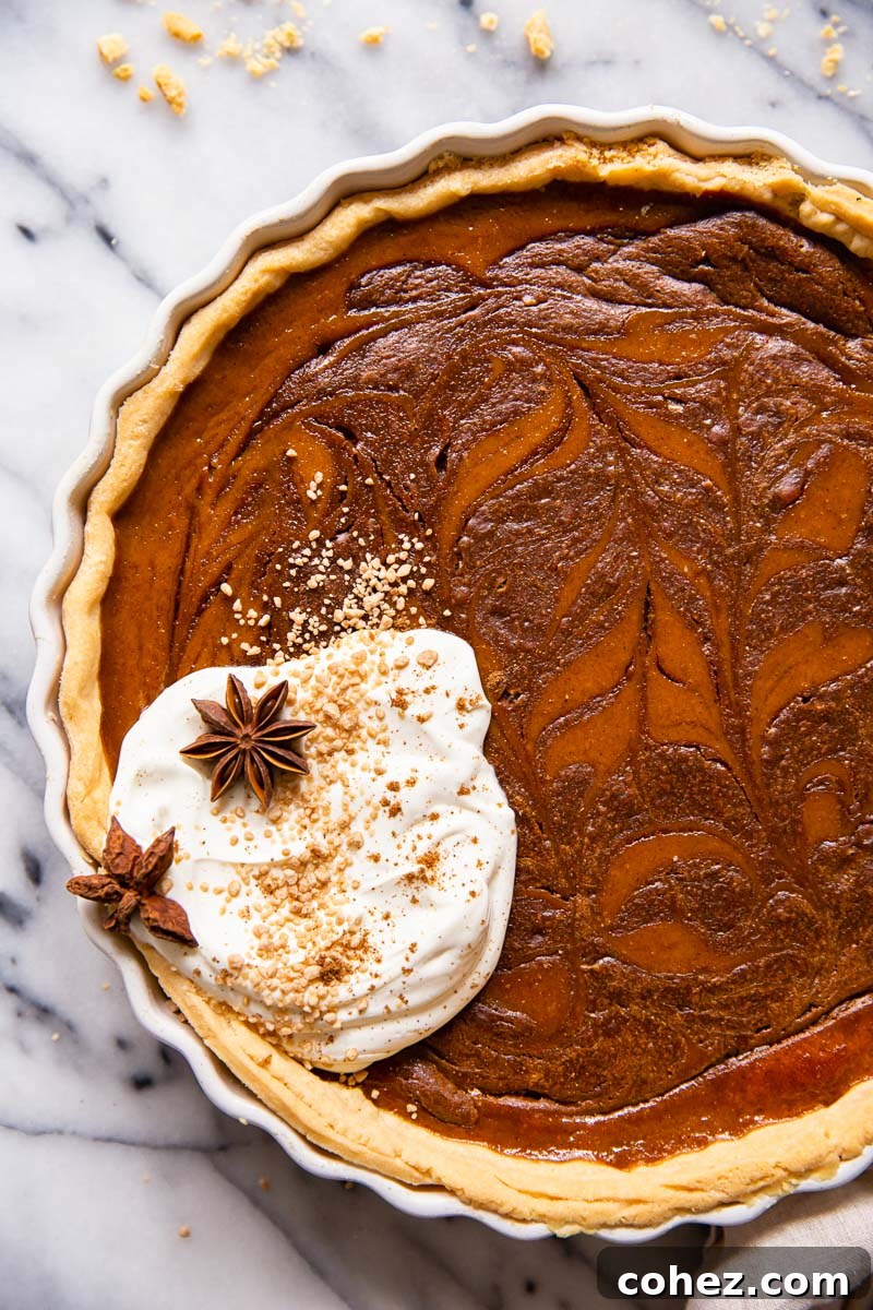 Pumpkin pie slice with a beautiful chocolate swirl, topped with a generous dollop of whipped cream, presented on a rustic wooden surface.