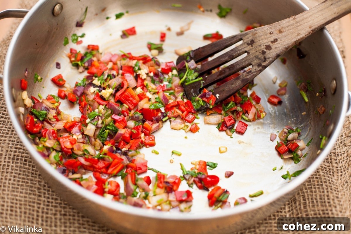 A bowl filled with freshly chopped vegetables like onions, bell peppers, and cilantro, ready for the next step in making the stuffed squash filling.