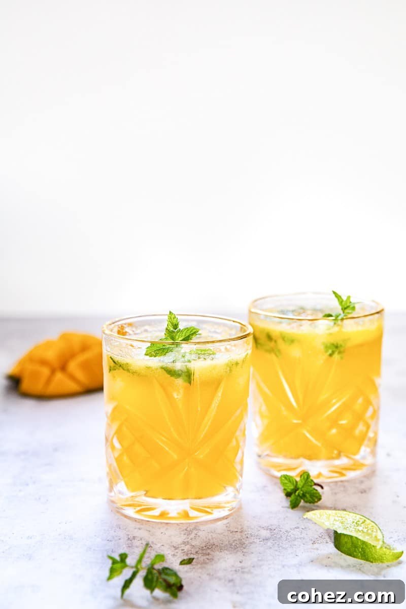 Close-up of a refreshing mango mojito in a tall glass, showing ice, mint, and lime slices. #mojito #cocktail #tropicaldrink