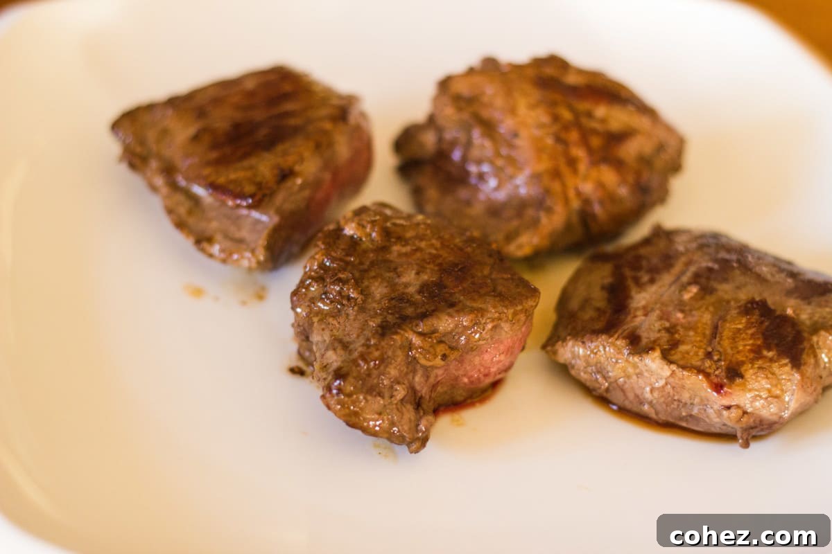 Perfectly browned venison steak resting on a white plate