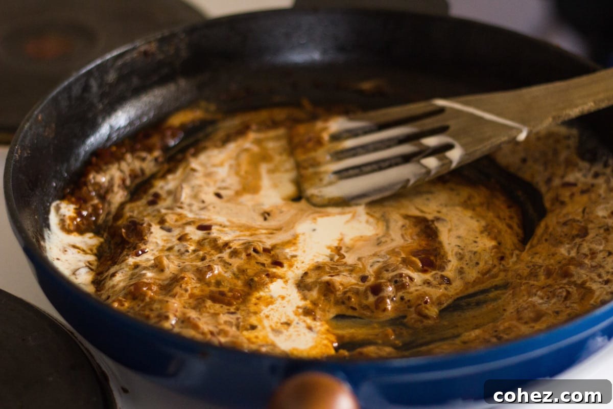 Cream being stirred into the finished Diane sauce in a pan