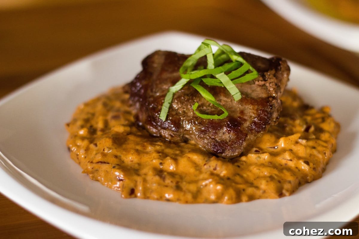 Close-up view of a perfectly cooked Venison Steak Diane on a white plate