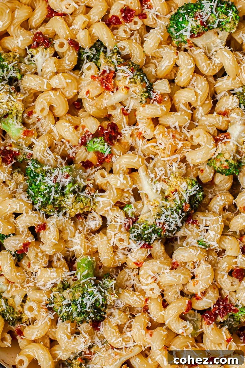 Sun-Kissed Tomato and Broccoli Pasta with Parmesan 4 An overhead shot of a prepared pasta dish featuring broccoli florets and sun-dried tomatoes, generously garnished with freshly grated Parmesan cheese.