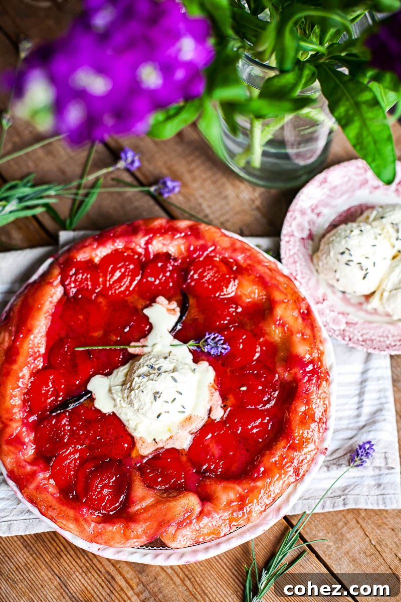 Plum tarte tatin on a wooden table, next to a vase with purple flowers