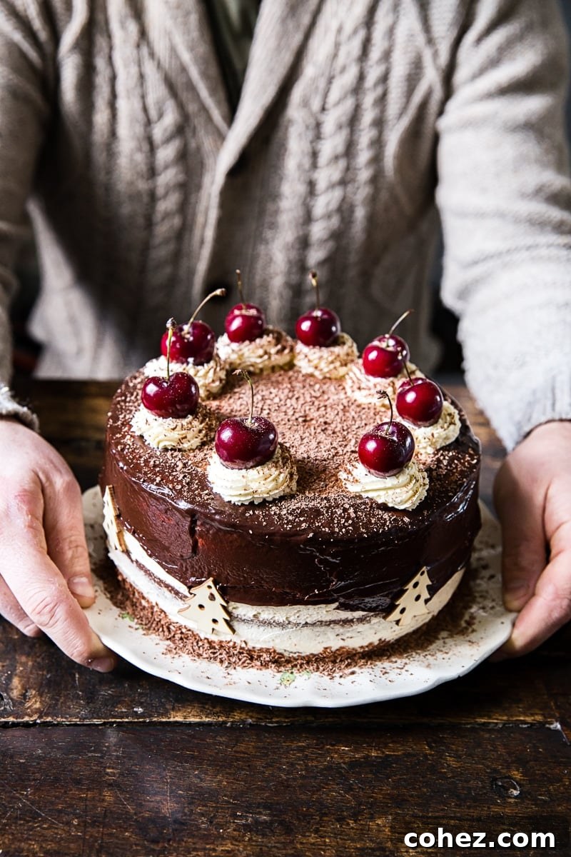 man holding a beautifully decorated chocolate Black Forest Cake