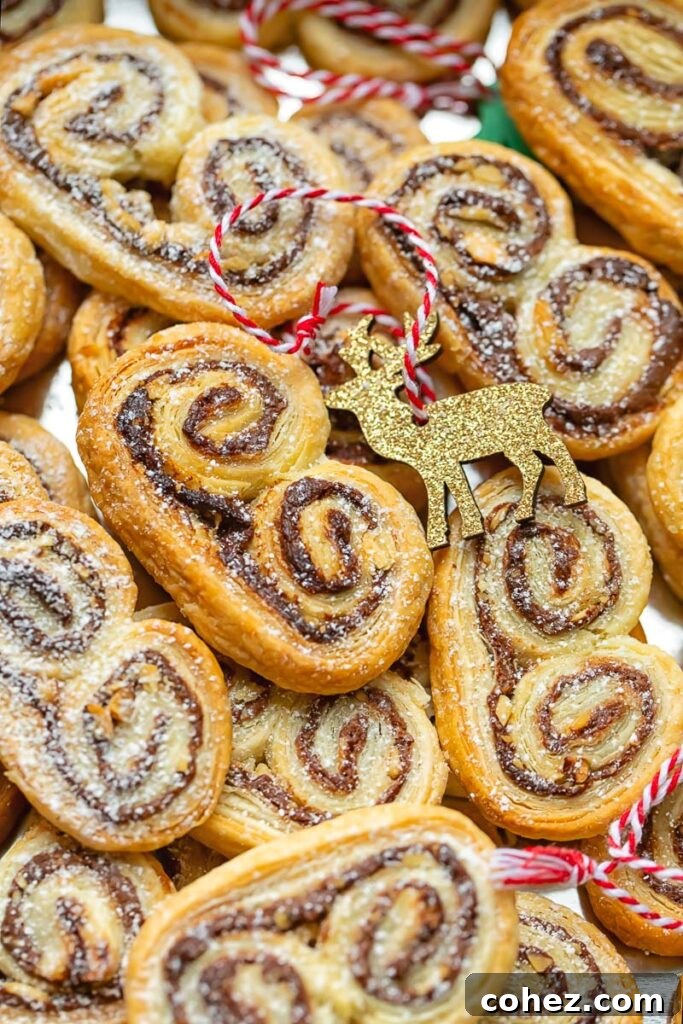 A close up view of palmiers piled together, golden and flaky with chocolate centers.