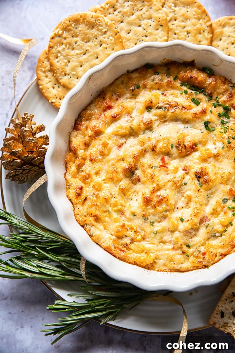 baked crab dip in white round dish with crackers and rosemary around the dish