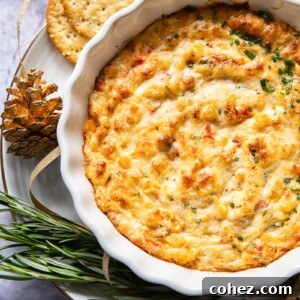 baked crab dip in white round dish with crackers and rosemary around the dish