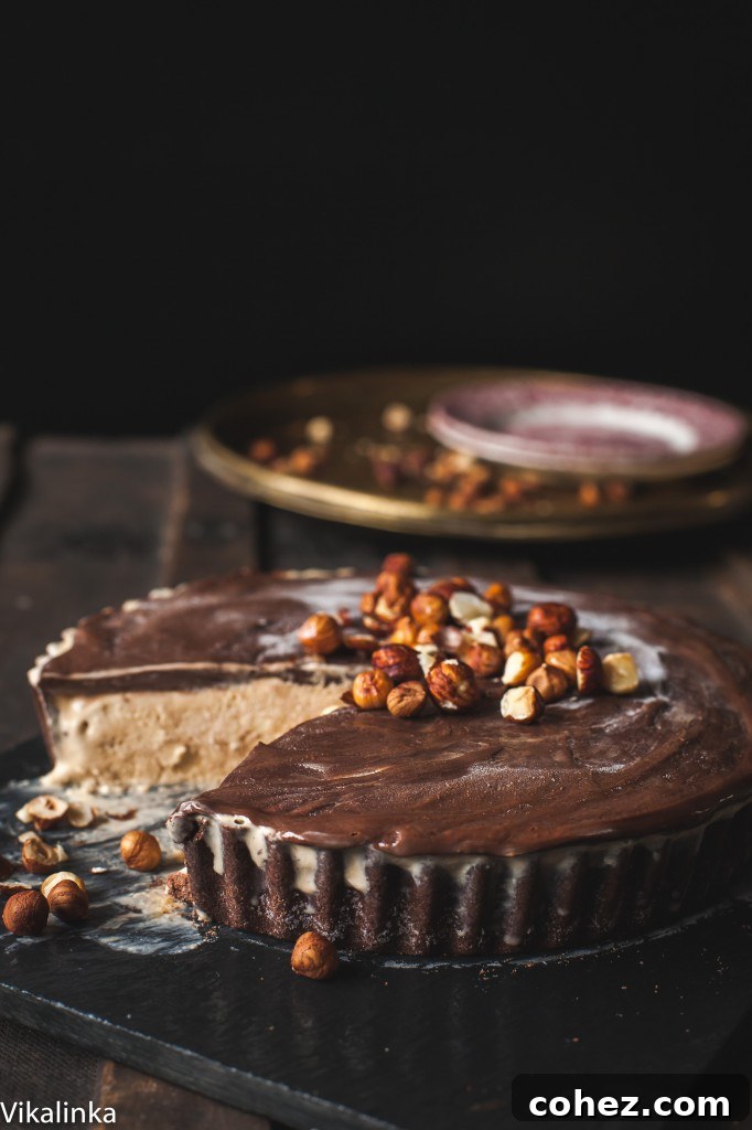 Spiced Autumn Mississippi Mud Pie 5 A whole Autumn Mississippi Mud Pie on a rustic table, with a slice removed and surrounded by scattered hazelnuts.