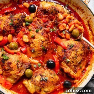 Chicken with red peppers, olives and white beans in a tomato sauce in a pan
