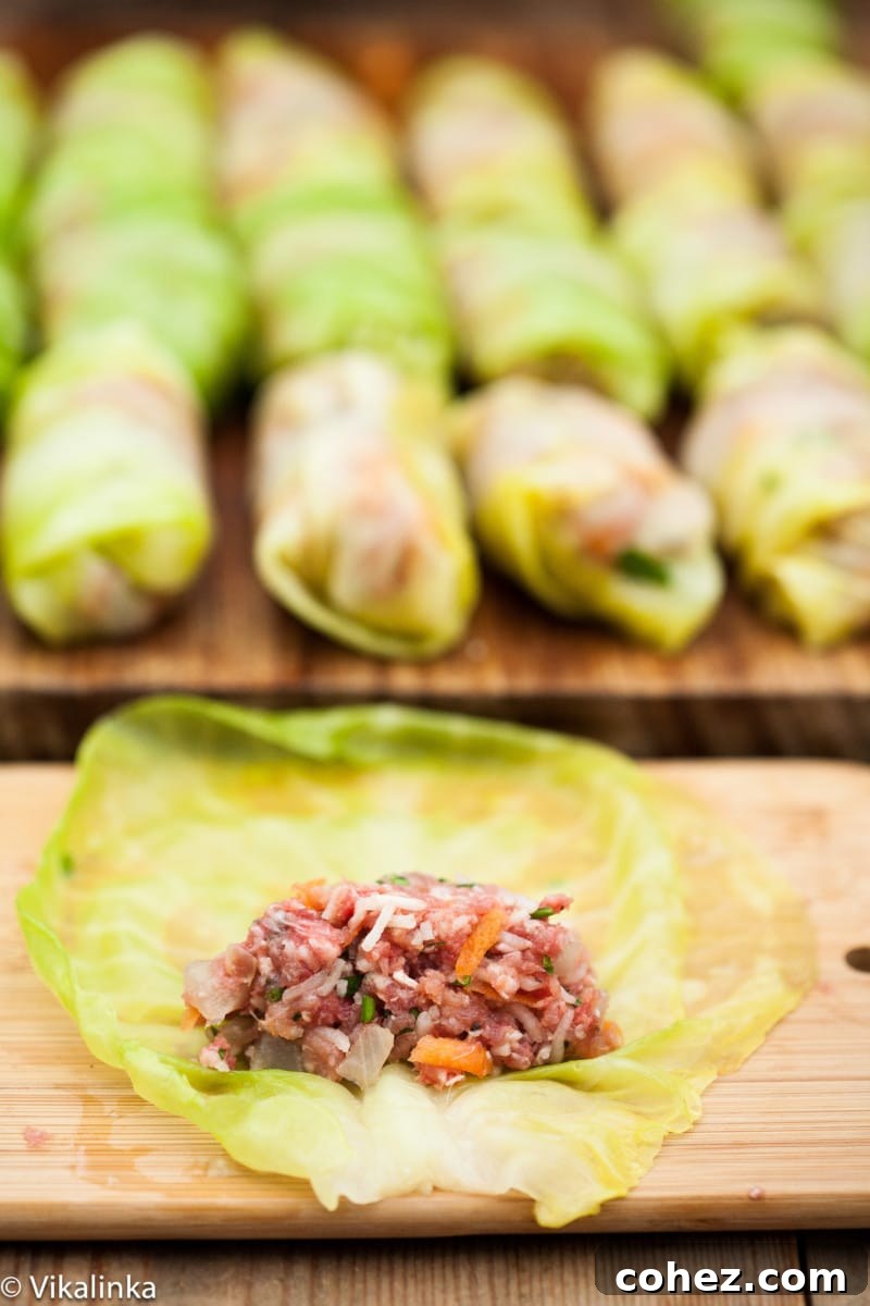 Grandma's Authentic Golubtsi Cabbage Rolls 5 A close-up of hands carefully rolling a cabbage leaf filled with the savory meat, rice, and vegetable mixture, demonstrating the preparation process for stuffed cabbage rolls.