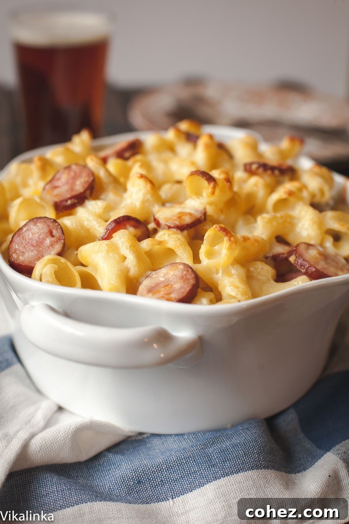 A golden-brown baked dish of mac and cheese with sausage on a wooden table.
