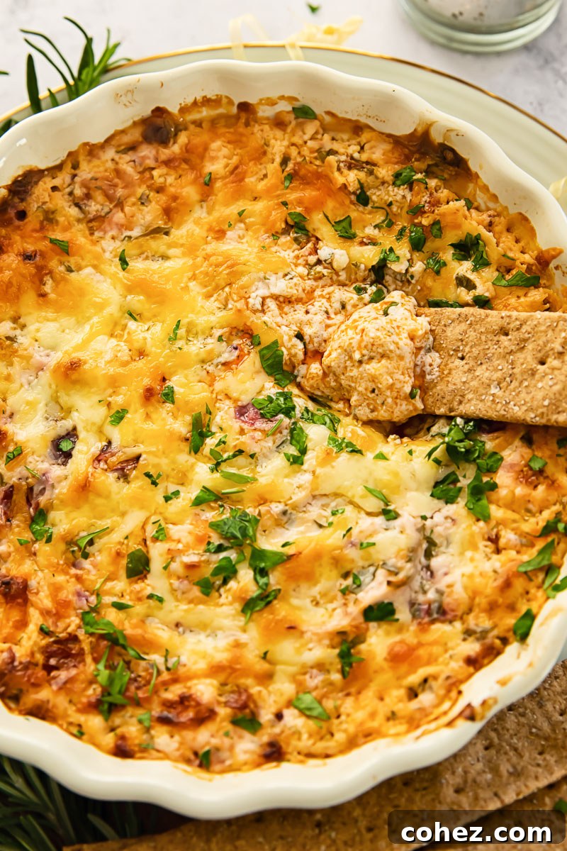 Hot cranberry and chorizo dip in a round serving dish with a cracker on the side, ready to be enjoyed.