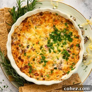 Top-down view of a small square dish of cranberry and chorizo dip with crackers.