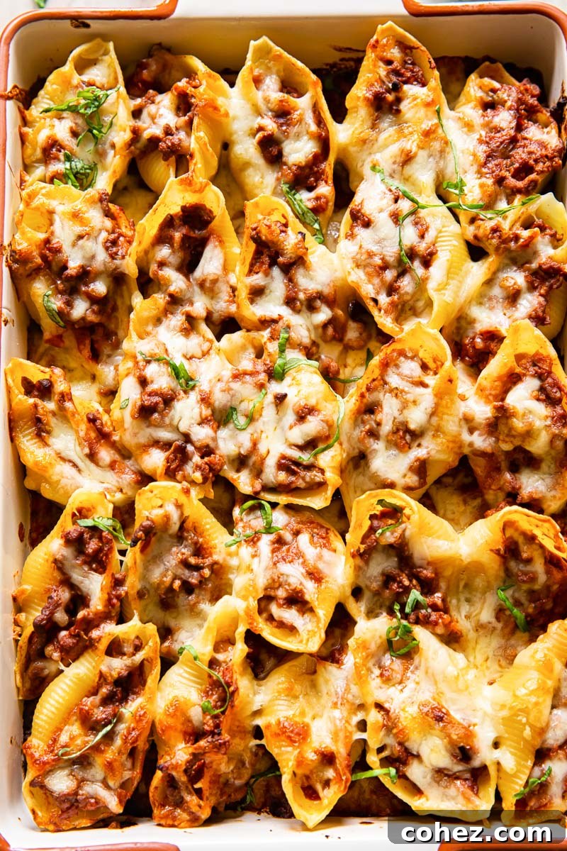 Effortless Stuffed Shells with Savory Pesto Beef Ragu 2 Close-up of beef stuffed giant pasta shells topped with melted mozzarella cheese, ready to be served from a baking dish.