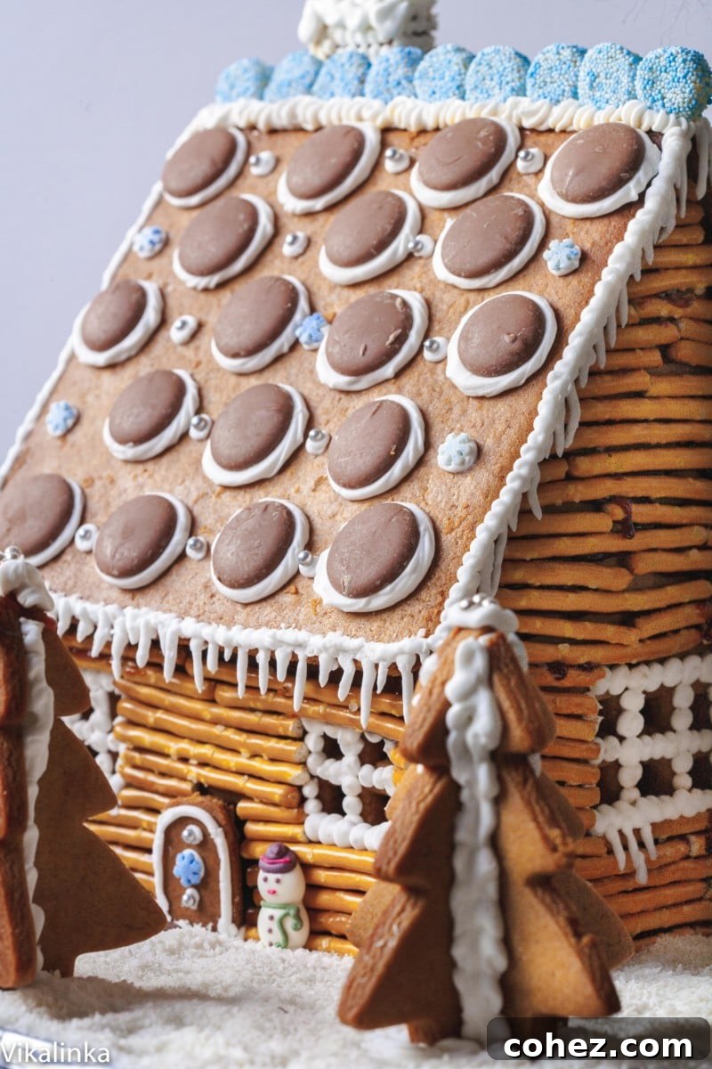 Gingerbread house made to look like a rustic cabin, assembled with pretzel logs