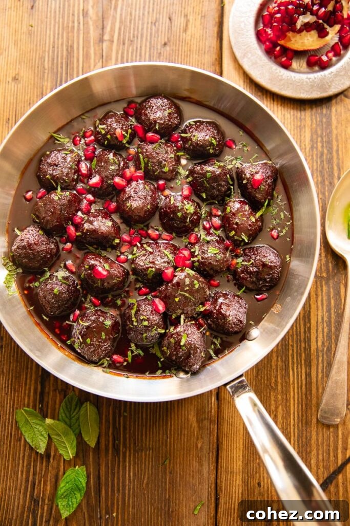 Pomegranate-Glazed Sweet and Sour Meatballs 2 Sweet and sour meatballs generously coated in pomegranate sauce, served in a skillet on a wooden table.
