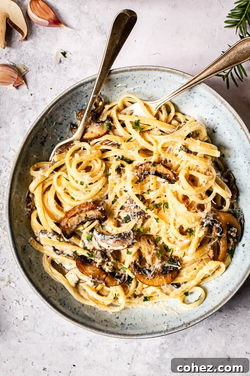 An inviting top-down view of a bowl of creamy pasta with mushrooms and bacon, showcasing its rich texture.
