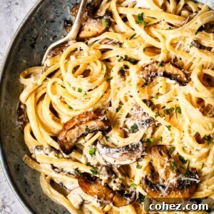 Creamy tagliatelle with bacon and Portobello mushrooms in a blue bowl with two forks, perfect for a cozy date night.