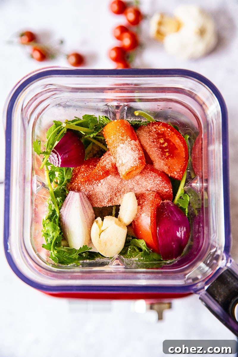 Fresh 5-Minute Blender Salsa 4 Fresh salsa ingredients, including quartered tomatoes, onion, garlic, and cilantro, placed inside a blender jar, ready for blending.