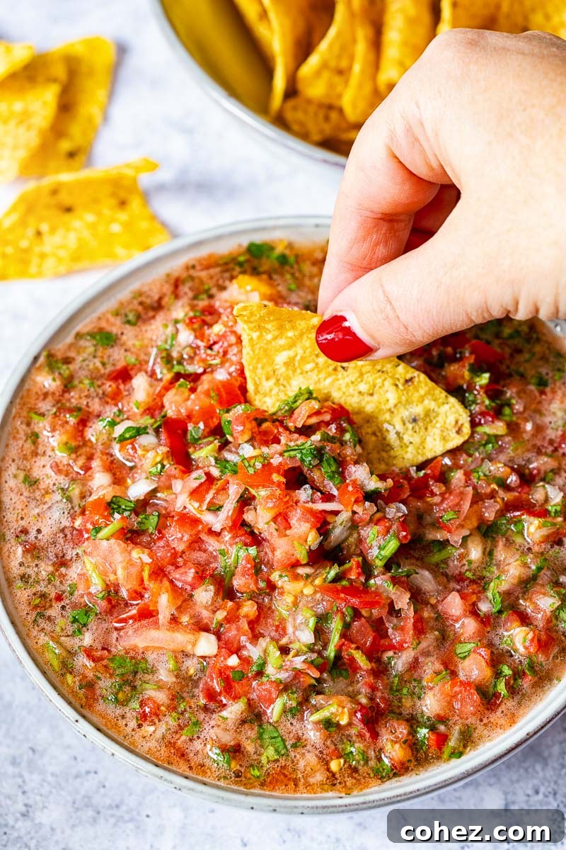 Fresh 5-Minute Blender Salsa 5 A vibrant bowl of fresh salsa fresca, richly red with green cilantro, placed on a rustic wooden surface, ready to be served.