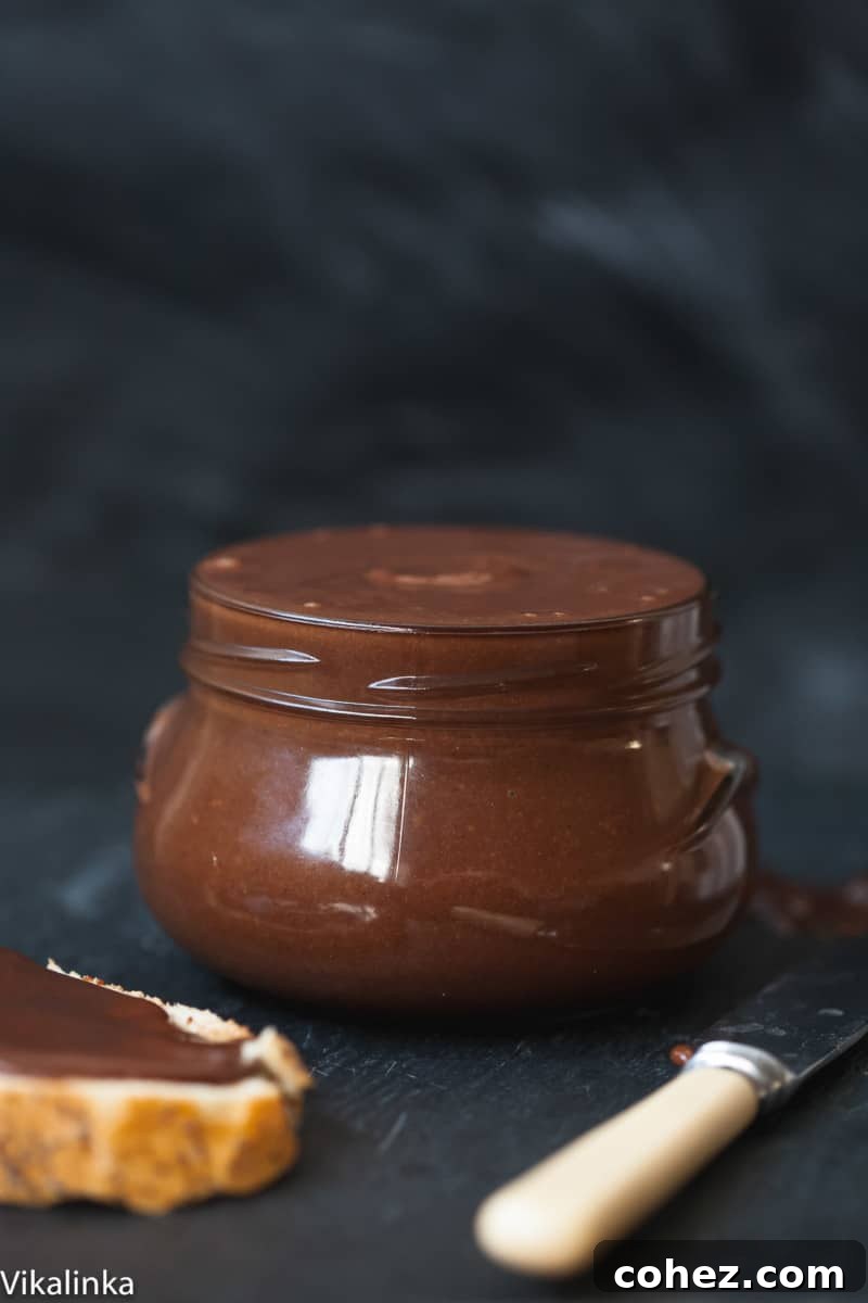 Side shot of homemade chocolate almond butter in a glass jar, showcasing its smooth and rich texture.