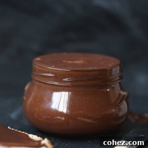 Side shot of homemade chocolate almond butter in a glass jar, showcasing its smooth and rich texture.