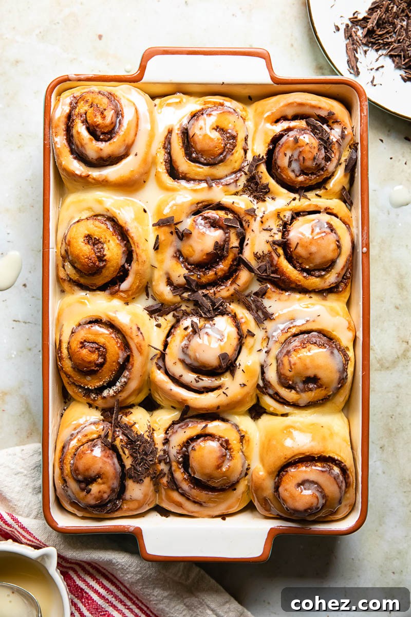 Chocolate Nutella Rolls with Glaze Top-down view of a tray of chocolate Nutella rolls, adorned with a sweet sugar glaze and scattered chopped chocolate.
