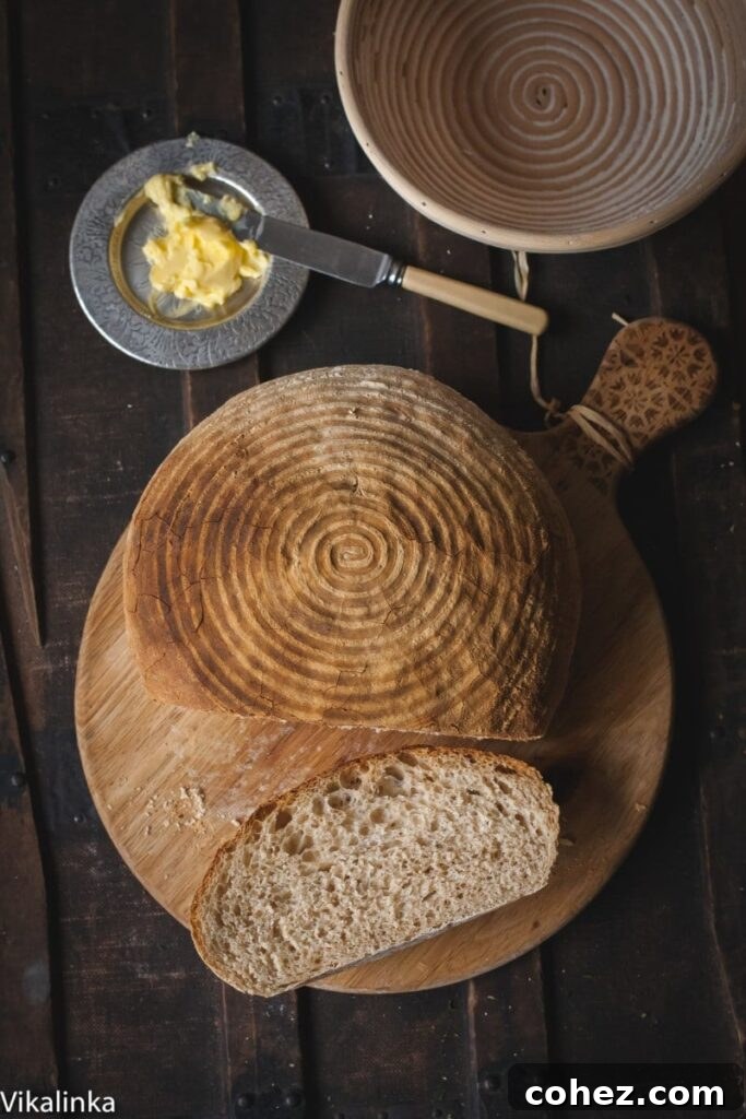 A whole loaf of Rosemary Spelt Bread with a deep, golden crust, ready to be sliced and enjoyed.