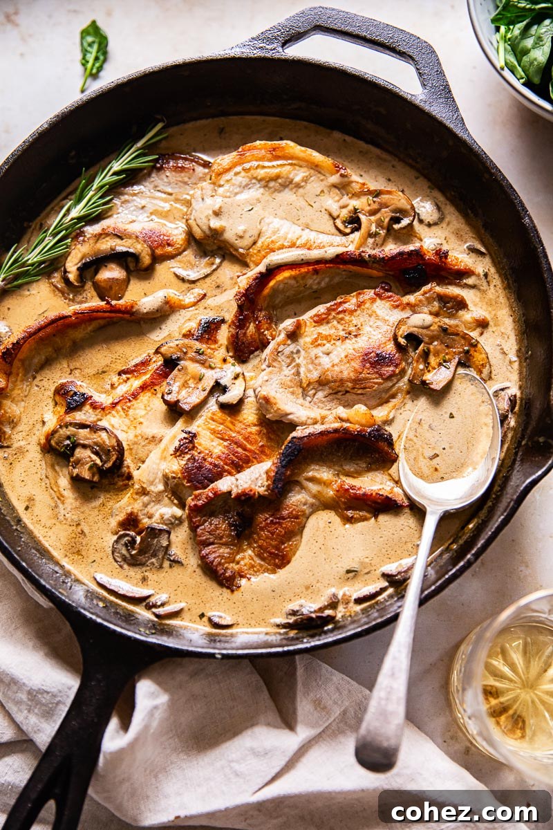 pork loin steaks in creamy sauce with mushrooms in black pan