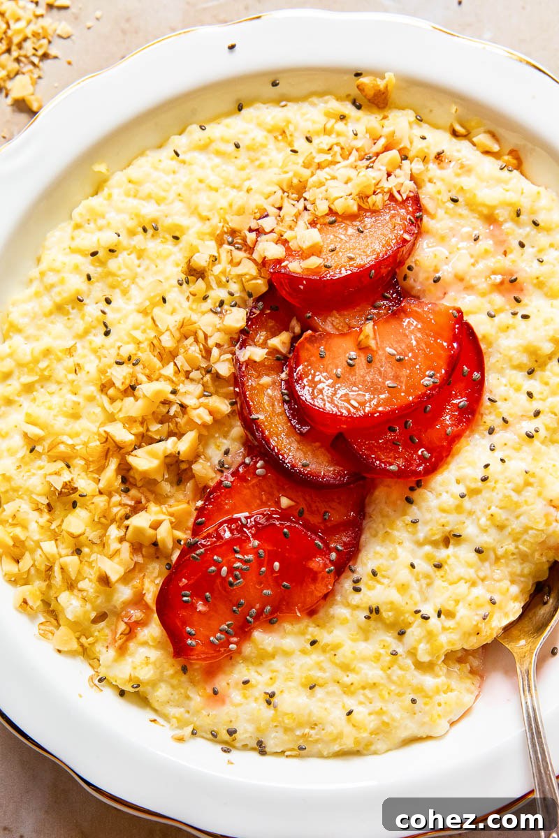 A vibrant close-up of millet porridge, beautifully garnished with glistening honey-glazed plums, crunchy walnuts, and tiny chia seeds, highlighting the appealing textures.