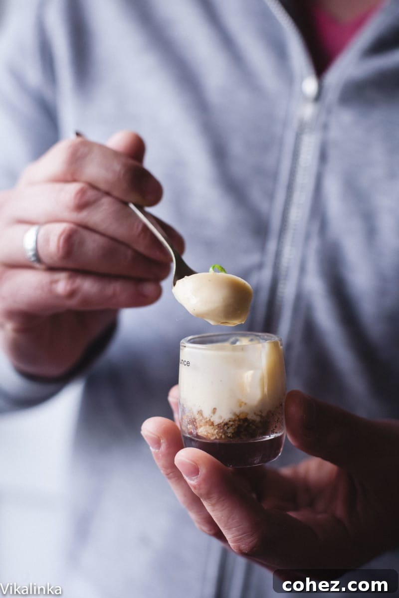 Velvety Lemon Vanilla Posset 6 A person holding a small shot glass filled with lemon posset, showing its smooth texture, ready to be eaten.